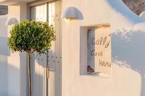 A white building with a small window displaying 'Cally Love House' text, a door, and a potted plant. - Apartment 'Holiday Home 55sqm' with Wi-Fi and Air Conditioning (Fira)