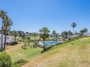 Uma área residencial com piscina, palmeiras e casas ao fundo.