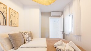A hotel room with a bed, a wall-mounted air conditioner, and a door leading to another room. - Modern apartment, panoramic view - 4 guests (Marbella)