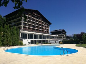 A hotel with a swimming pool, multiple balconies, and a mountain view. - Charming lodging in Megève - 6 guests (Megève)