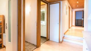 A hallway with wooden flooring, a staircase, and a view into a room with a white door. - Charming lodging in Megève - 6 guests (Megève)
