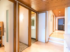 A hallway with wooden flooring, a staircase, and a view into a room with a white door. - Charming lodging in Megève - 6 guests (Megève)