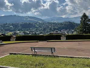 A park with a bench, a paved area, and a view of a town and mountains in the distance. - Charming lodging in Megève - 6 guests (Megève)