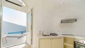 A compact kitchen with a view of the ocean, a built-in oven, and a small sink. - Apartment 'One Bedroom House 25sqm' with Wi-Fi and Air Conditioning (Fira)