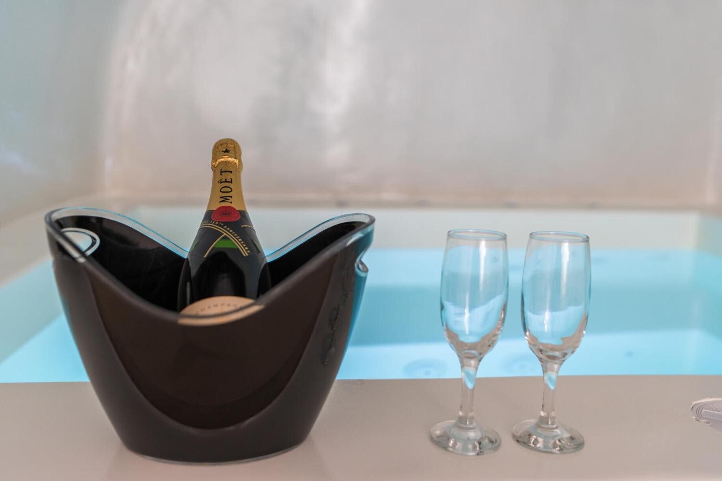 A black cocktail bowl with a bottle of Moët champagne and two empty champagne flutes on a table.