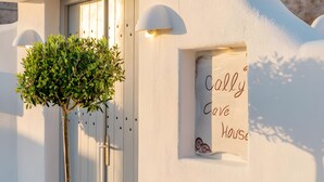 A white building with a small window displaying 'Cally Love House' text, a door, and a potted plant. - Apartment 'One Bedroom House 25sqm' with Wi-Fi and Air Conditioning (Fira)
