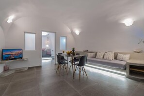 A modern living space with a dining area, a flat-screen TV, and a sofa with patterned cushions. - Apartment 'Holiday Home 28sqm' with Wi-Fi and Air Conditioning (Fira)