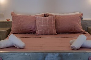 A bed with a pink bedspread and two pillows, one with a grid pattern and another plain. - Apartment 'Holiday Home 28sqm' with Wi-Fi and Air Conditioning (Fira)