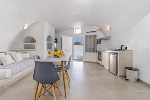 A modern, open-plan living space with a dining area, kitchenette, and a view of the outdoors. - Apartment 'Holiday Home 28sqm' with Wi-Fi and Air Conditioning (Fira)