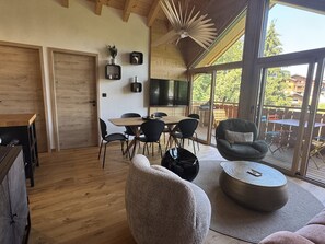 A modern interior with a dining area, seating, and a large window offering a view. - Apartment with private parking - 6 guests (Les Carroz d'Arâches)
