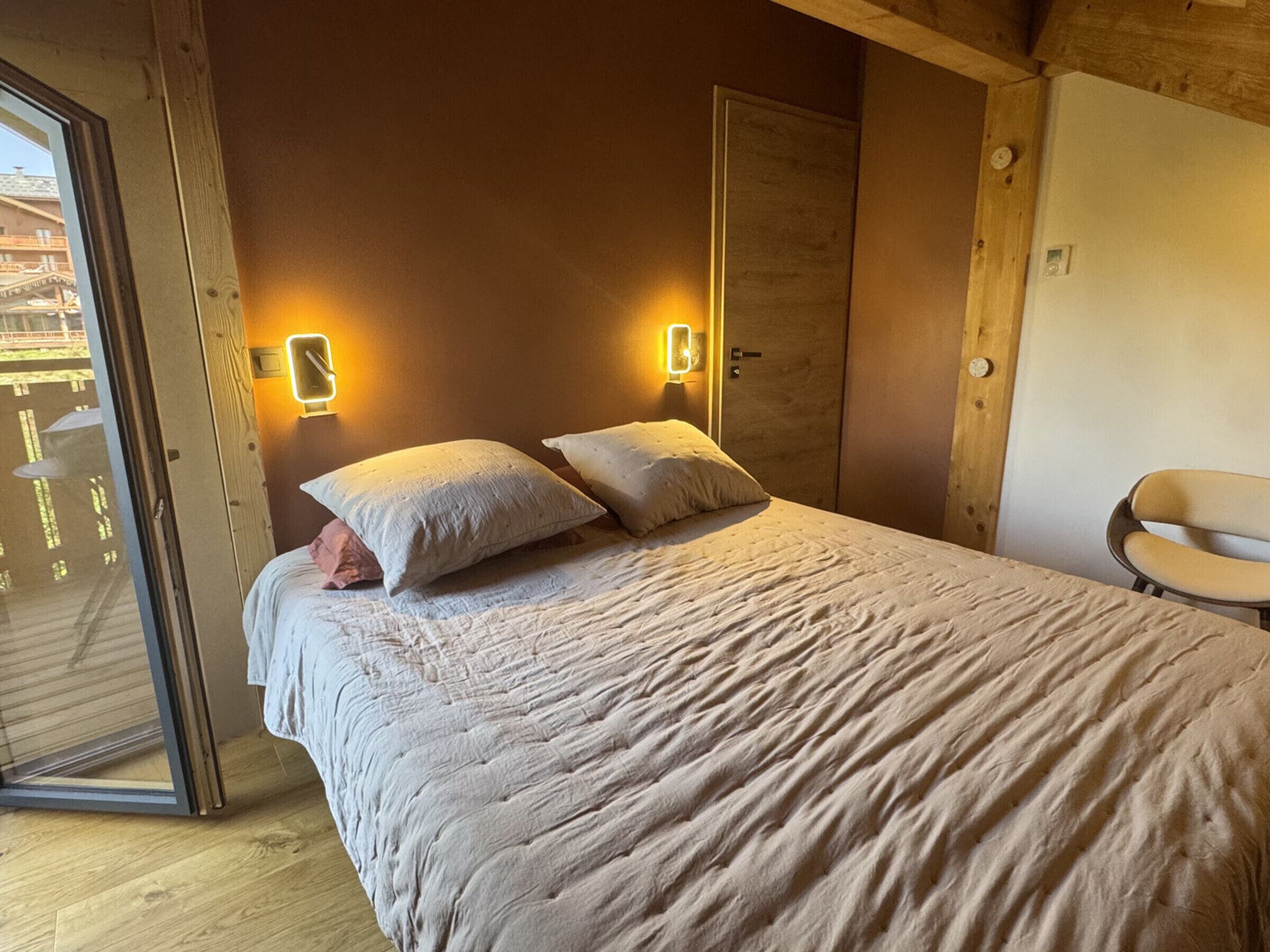 Ein Schlafzimmer mit Bett, Kissen, einem Sessel und einer Schiebetür.
