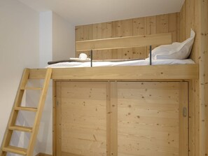 A bunk bed with a wooden ladder and a wardrobe with a sliding door.