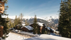 A snow-covered mountain landscape with wooden cabins and pine trees.