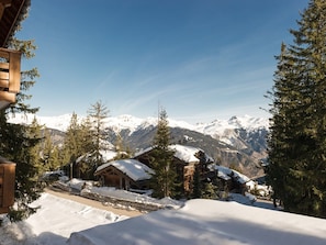 Schneebedeckte Berglandschaft mit Holzhütten und Kiefern.