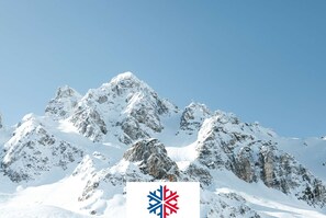 A snow-covered mountain range with a logo in the foreground.