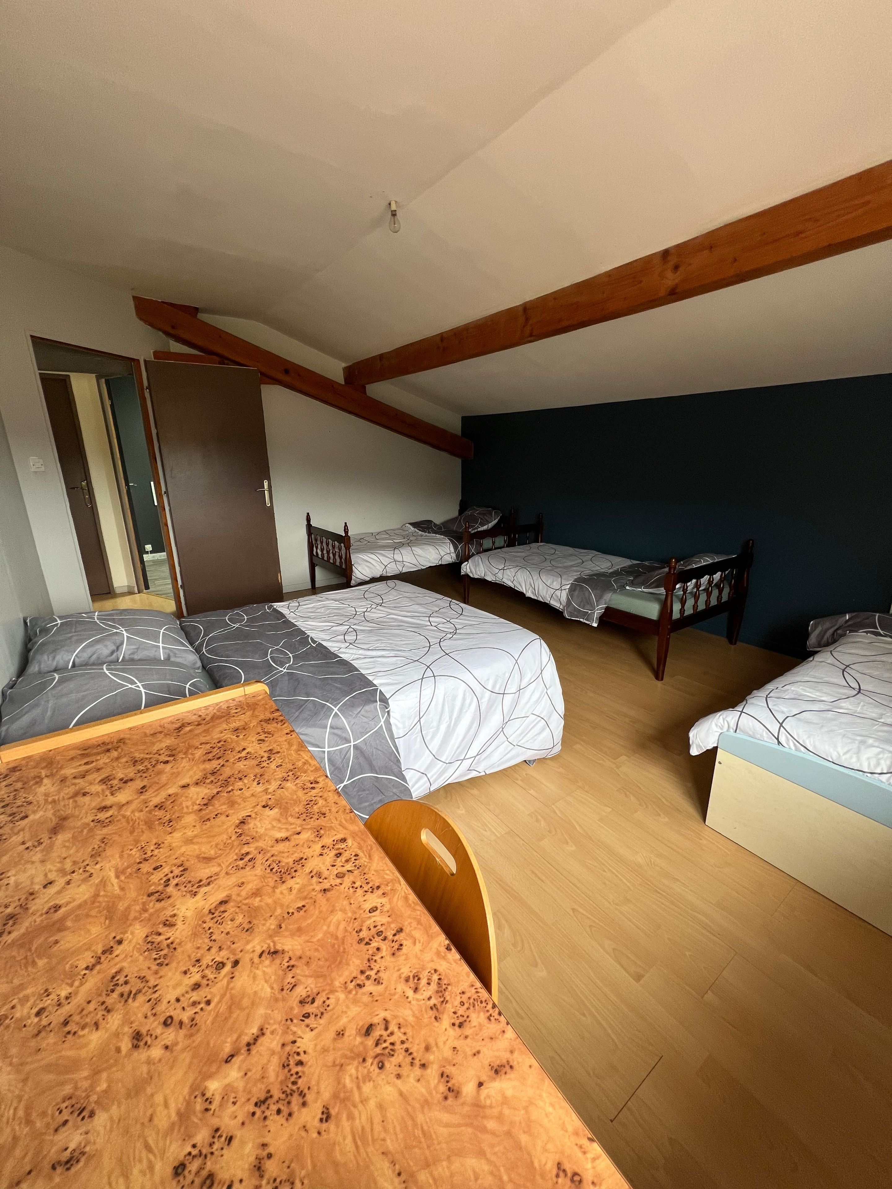 Une pièce avec deux lits, une table en bois et une porte.