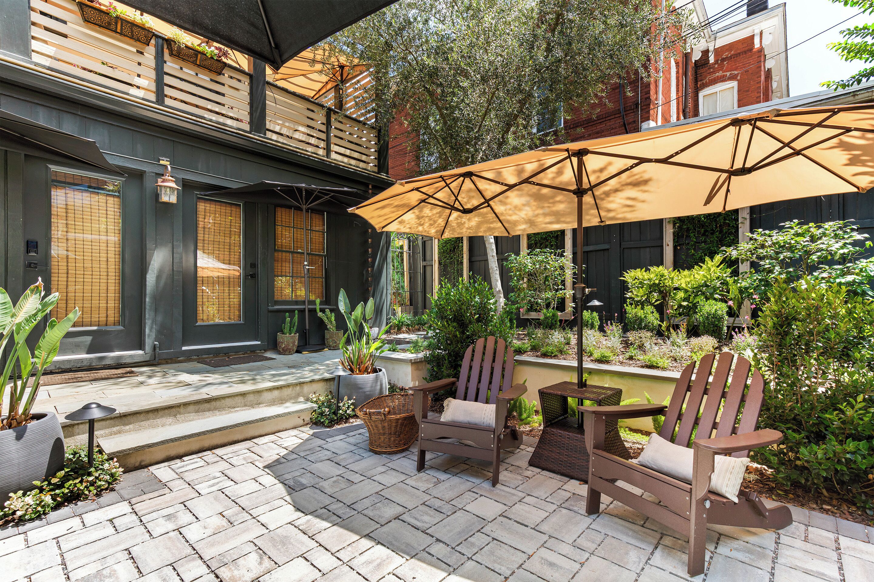 Une terrasse extérieure avec une chaise en bois, une table et un grand parasol.