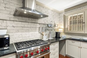A kitchen with a stainless steel stove, a range hood, and white cabinetry. - Hidden Garden Retreat | One-Level Near Forsyth By Lucky Savannah (Savannah)