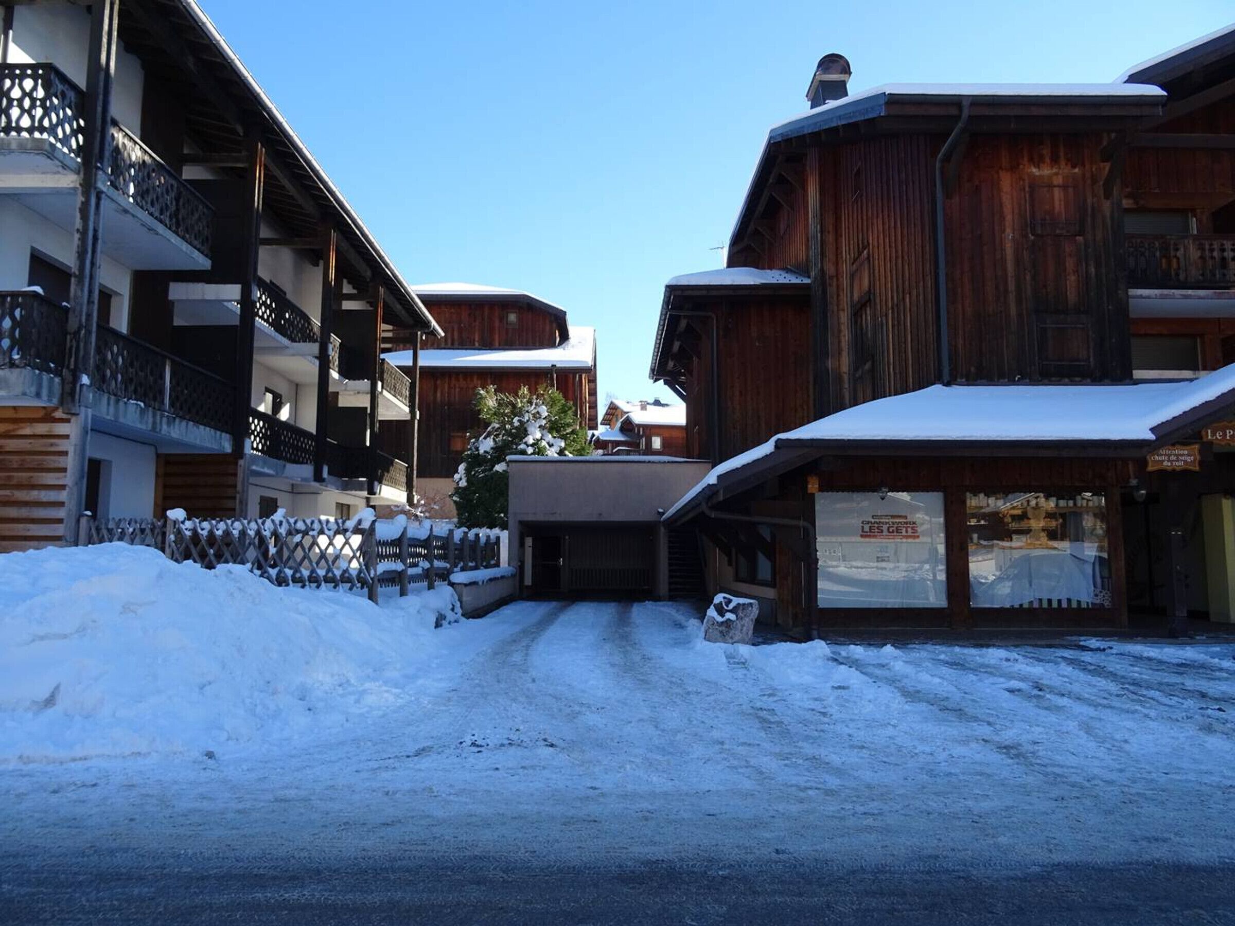A snow-covered street with wooden buildings, including a visible sign for a restaurant.