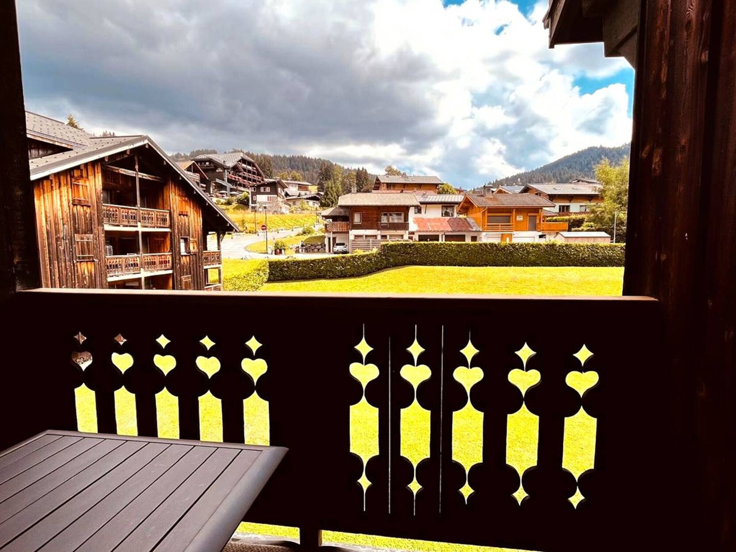 Un bâtiment en bois doté d’un balcon, offrant une vue sur un village et, au loin, sur une montagne.