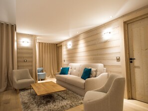 Een moderne woonkamer met een beige bank, twee fauteuils, een houten salontafel en een zacht tapijt.