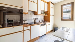 Una cocina moderna con horno empotrado, lavavajillas y una ventana sobre el fregadero.