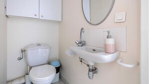 Un baño con inodoro, lavamanos, espejo y armario.