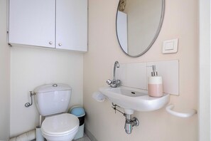 Ein Badezimmer mit Toilette, Waschbecken, Spiegel und Schrank.