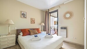 Habitación de hotel con cama, mesitas de noche, ventana con cortinas, radiador en la pared y vistas al exterior.