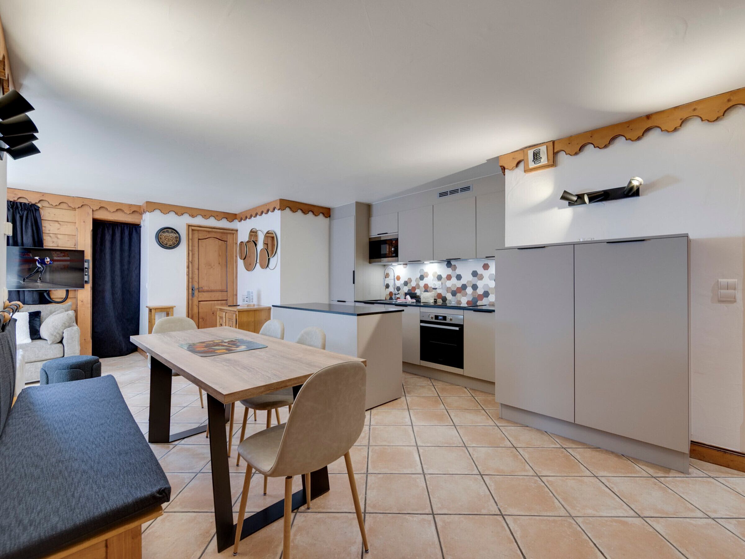 A compact kitchen with a dining area, featuring a wooden table, chairs, and a built-in oven.