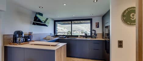 A modern kitchen with a large window, built-in appliances, and a herringbone wood floor.