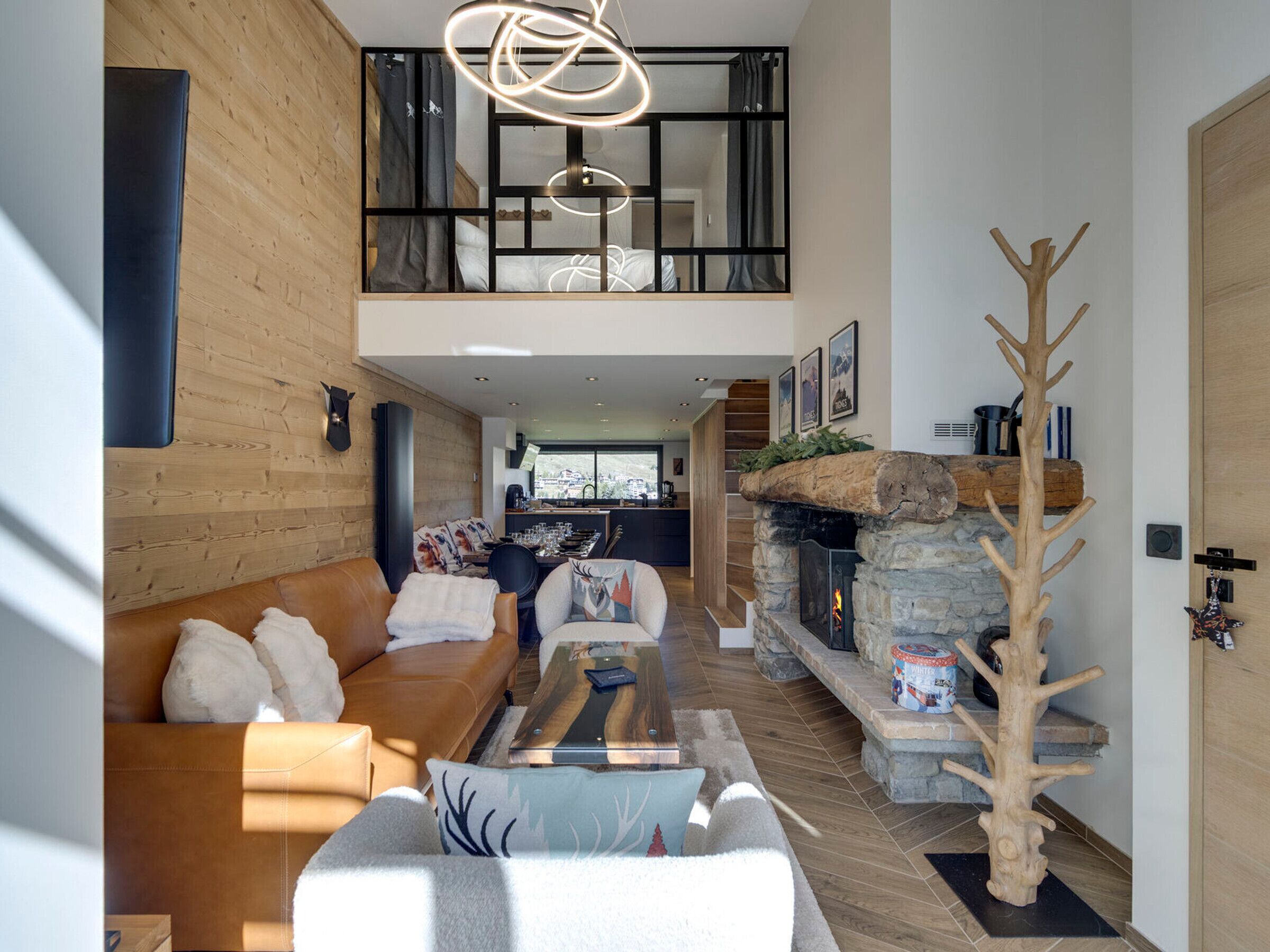Un salón moderno con techo alto, chimenea de piedra y una escultura de árbol de madera.