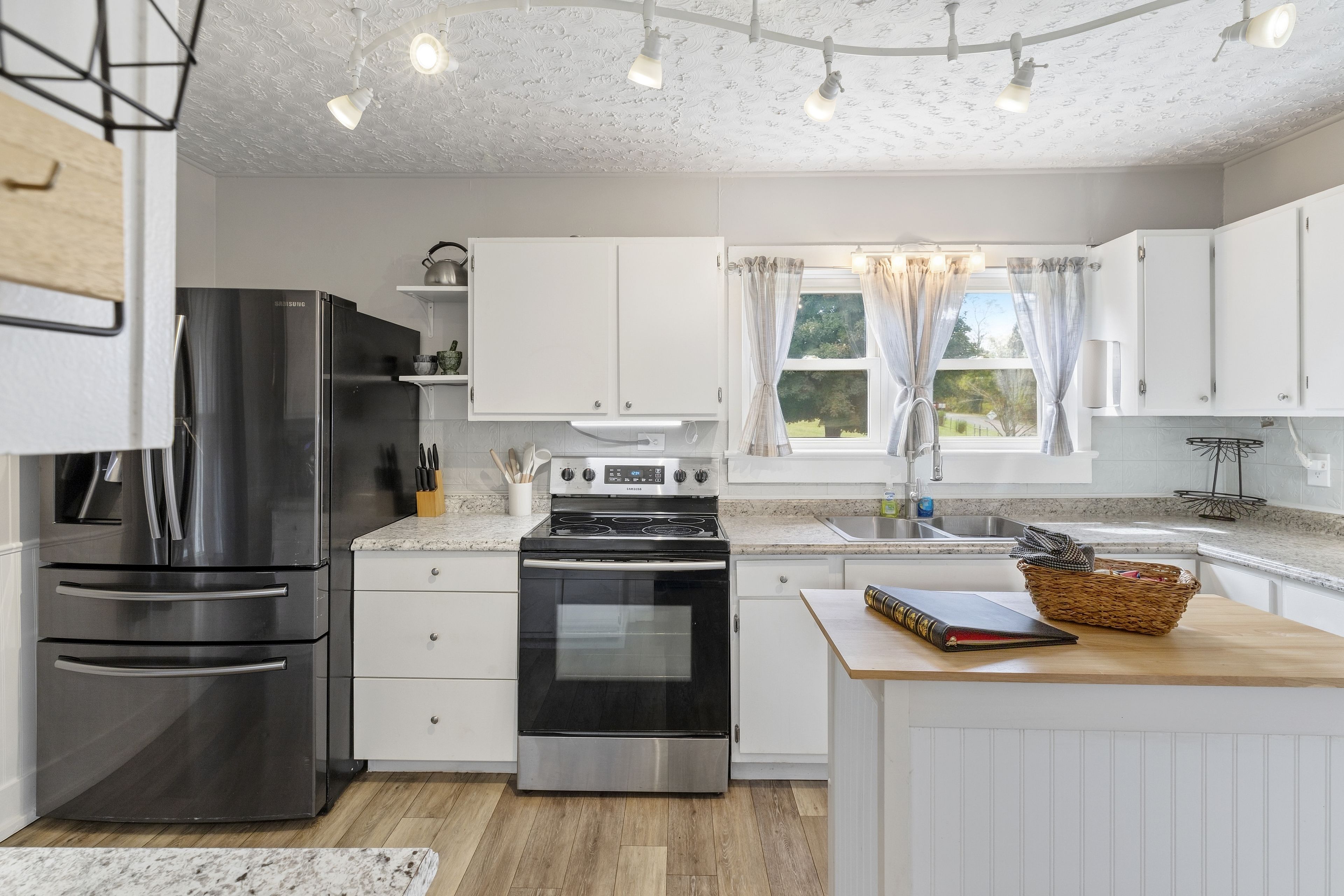 Una cocina moderna con electrodomésticos de acero inoxidable, armarios blancos y una isla de madera.