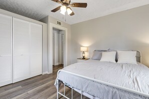 A bedroom with a bed, a nightstand, a ceiling fan, and a walk-in closet.