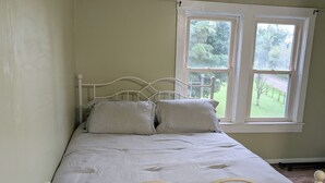 Un lit simple avec un cadre en métal, dans une pièce dotée d’un plafond en pente et d’une fenêtre.