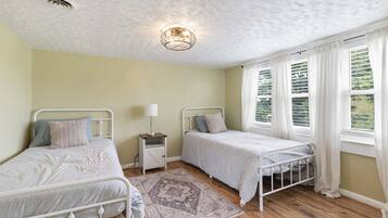 Een kamer met twee eenpersoonsbedden, een nachtkastje met lamp, een kamerbreed tapijt met patroon en een plafondlamp.