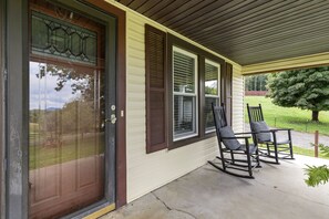 Une entrée de maison avec une porte d’entrée, un porche couvert et deux fauteuils à bascule.