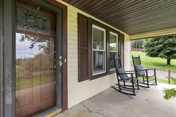 A house entrance with a front door, a covered porch, and two rocking chairs.