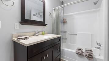Une salle de bain équipée d’une baignoire, d’une douche, d’un lavabo, d’un miroir et d’un porte-serviettes.