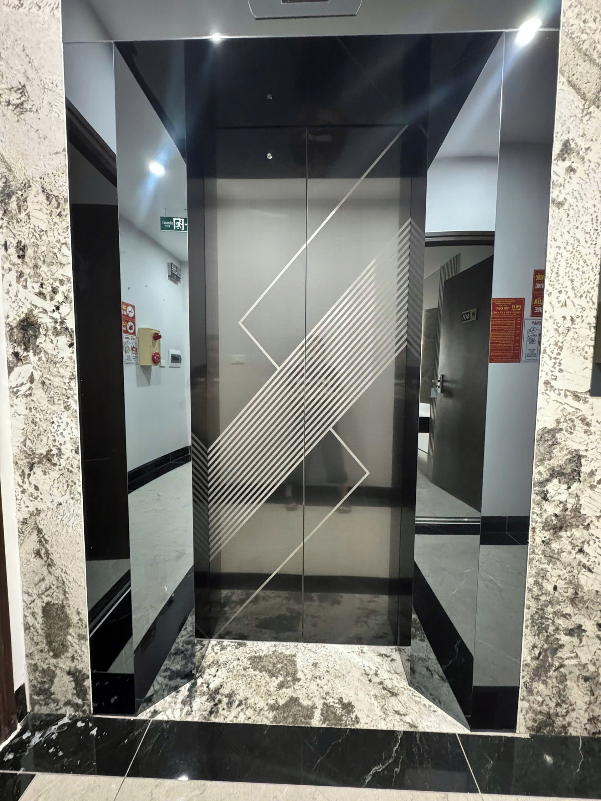 Ein Aufzug mit geometrischem Design an den Türen und einem Marmorboden.