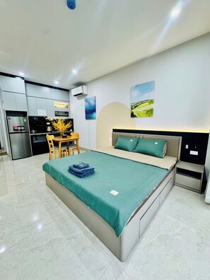 A modern bedroom with a bed, bedside tables, and a dining area with chairs.