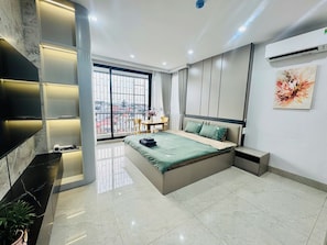Ein modernes Schlafzimmer mit einem großen Bett, einem an der Wand montierten Fernseher und einem Balkon mit Blick.