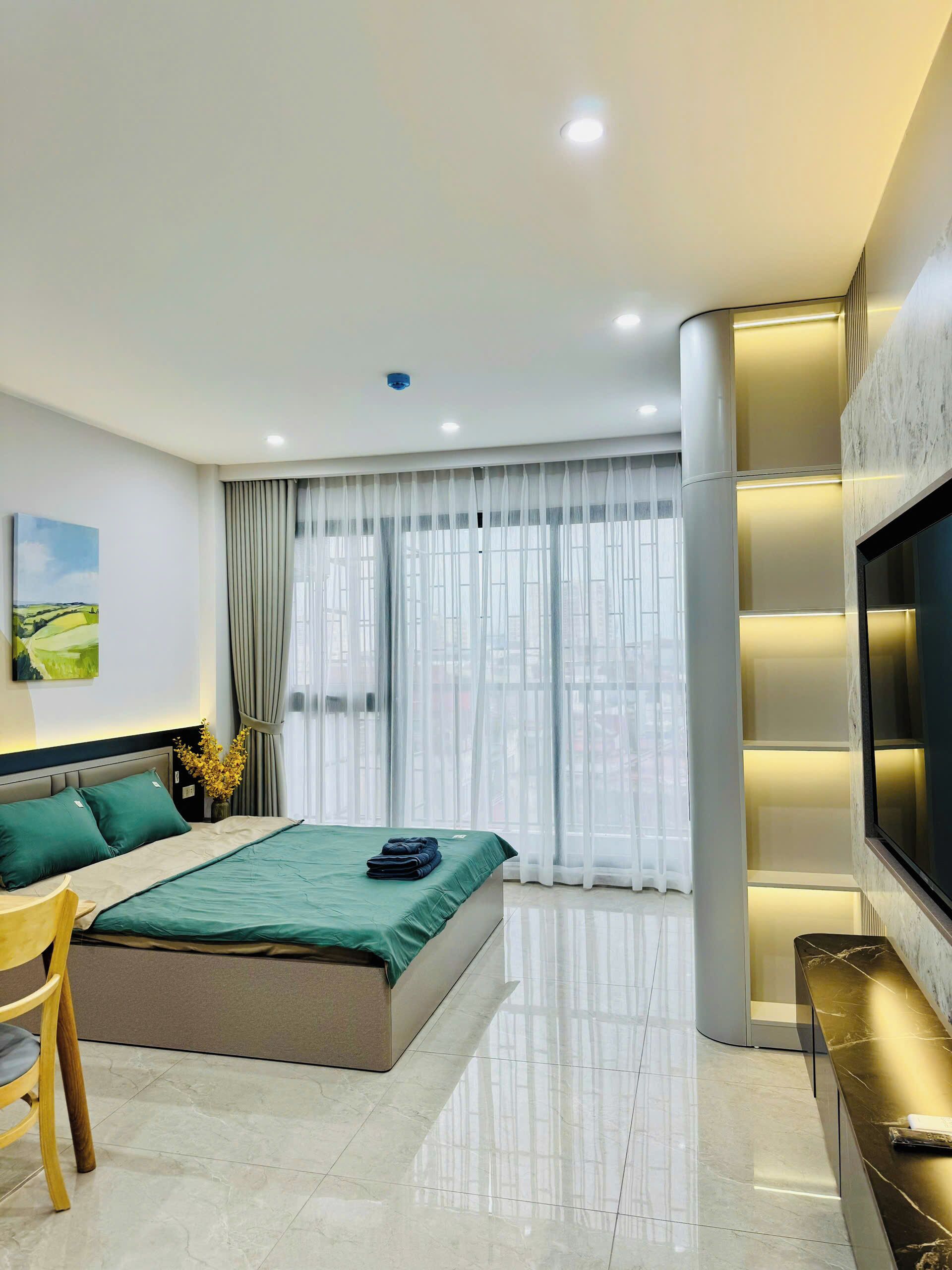 A modern bedroom with a bed, a TV, and a desk area.