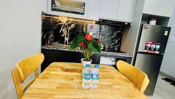 Una mesa de comedor con dos sillas, un florero con flores y una botella de agua.
