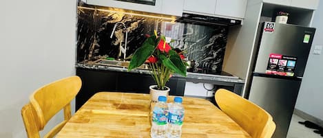 Une table à manger avec deux chaises, un vase avec des fleurs et une bouteille d’eau.