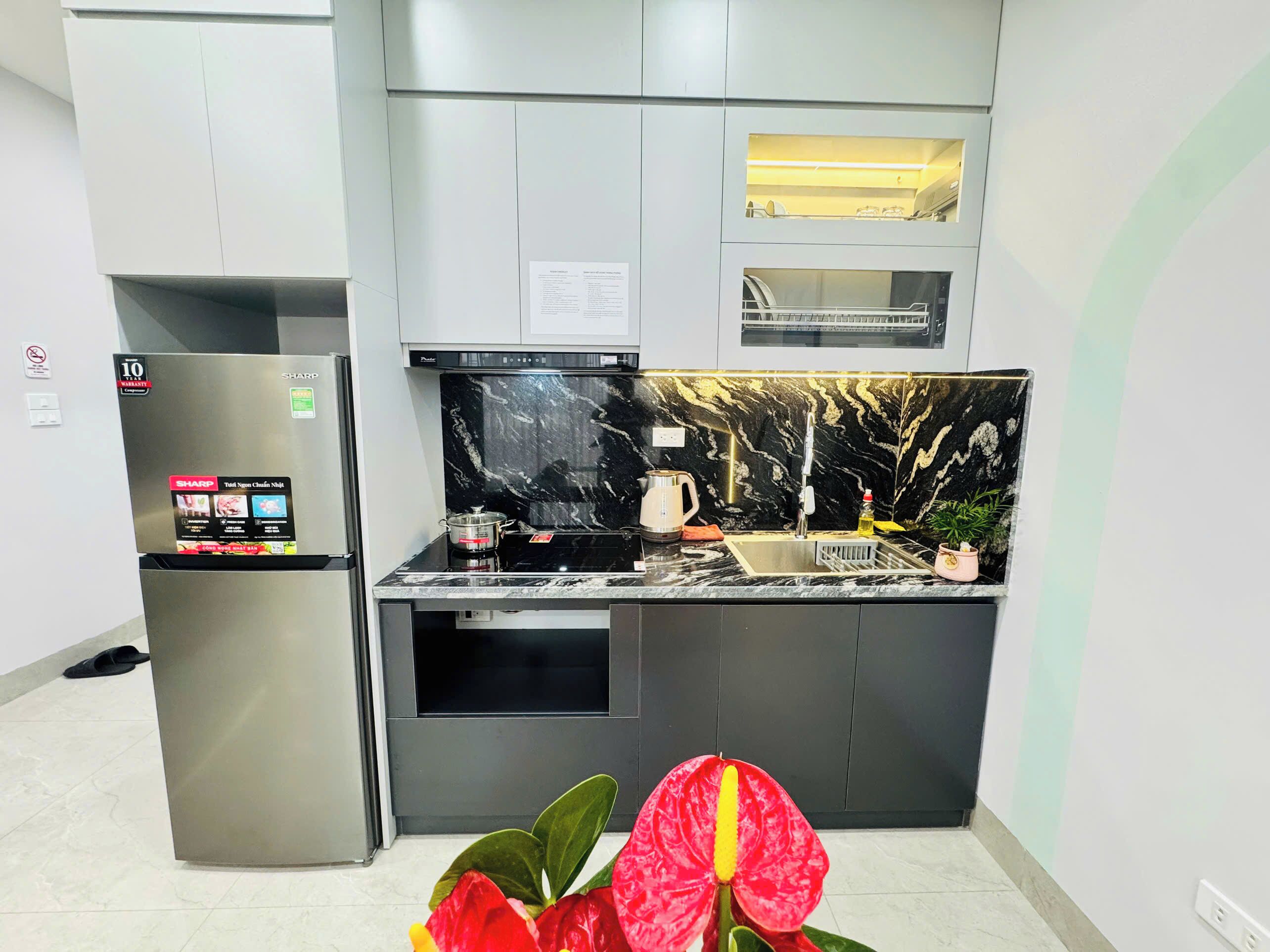 A modern kitchen with a built-in oven, a stainless steel refrigerator, and a black marble backsplash.