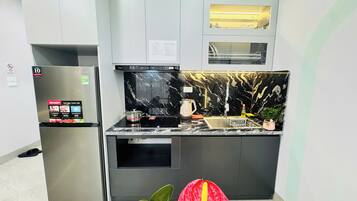 A modern kitchen with a built-in oven, a stainless steel refrigerator, and a black marble backsplash.