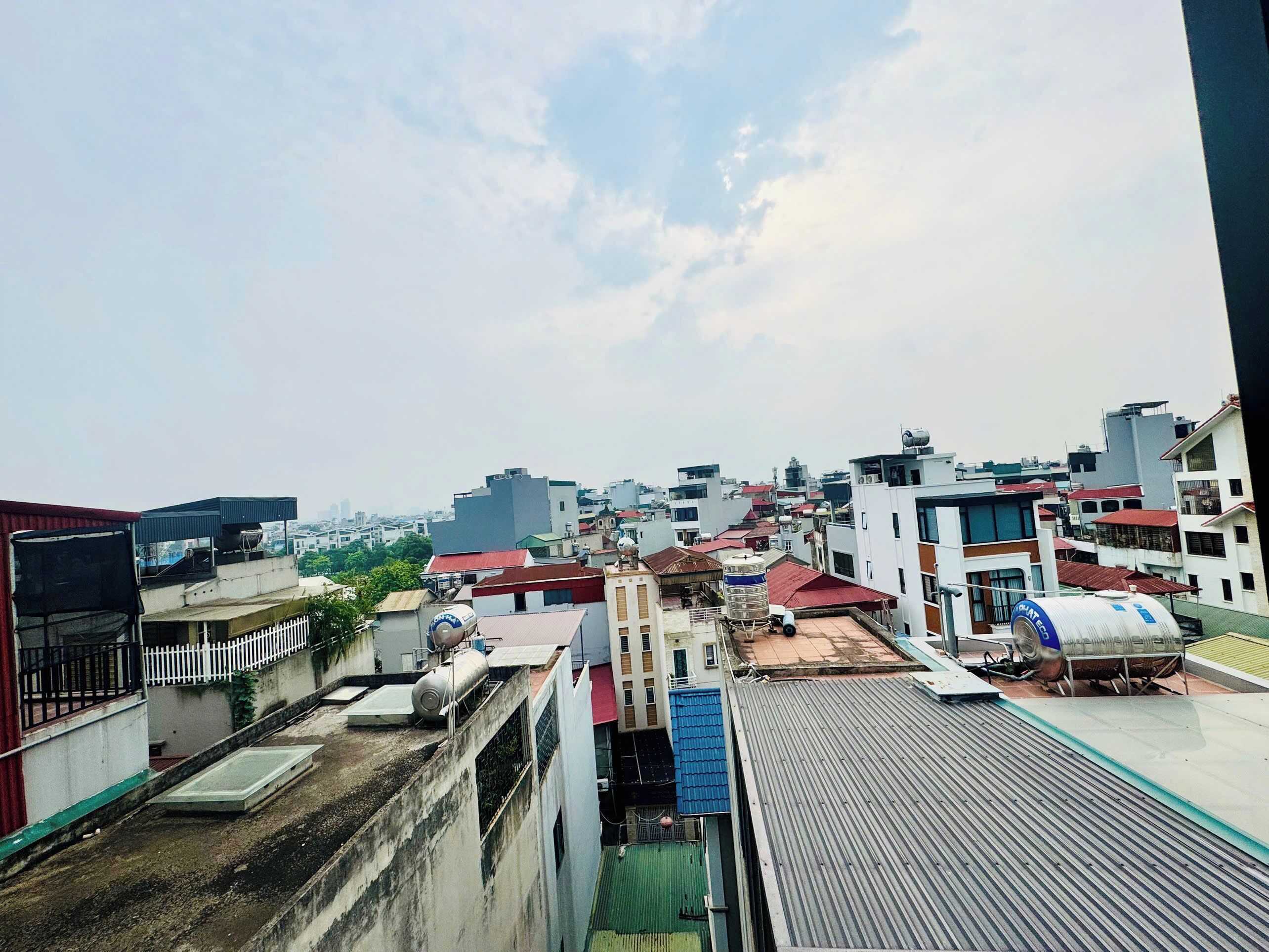 A cityscape with multiple buildings, some with flat roofs and others with sloped roofs, and a clear sky above.