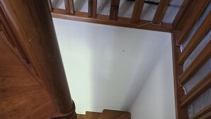 A wooden spiral staircase with a white wall and a mesh ceiling. - APPARTEMENT DUPLEX RESIDENCE DU PARC (Saint-Nectaire)