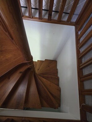 Eine Wendeltreppe aus Holz mit einer weißen Wand und einer Drahtgitterdecke.